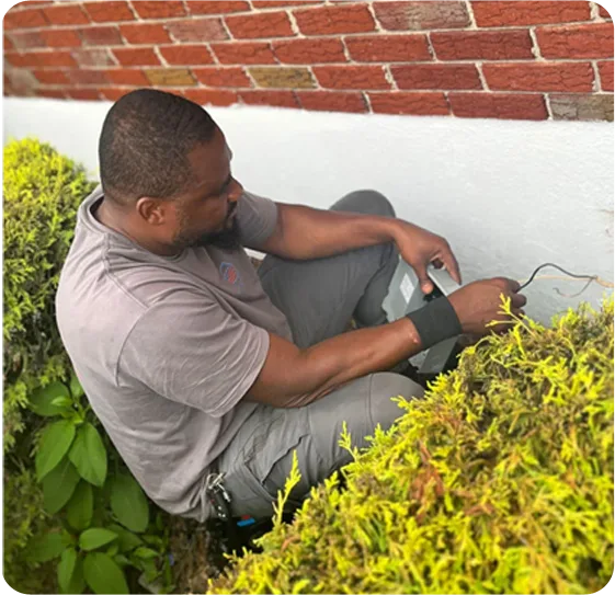 Professional technician inspecting outdoor HVAC or electrical system near residential property