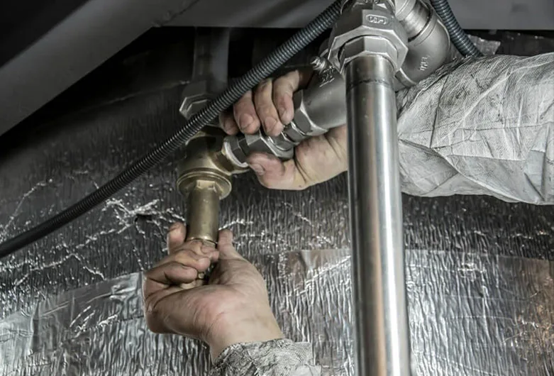 Plumber repairing water pipe connection and valve assembly in residential system