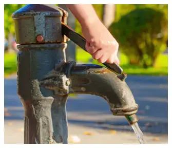 Outdoor water pump with running tap indicating well water supply system maintenance