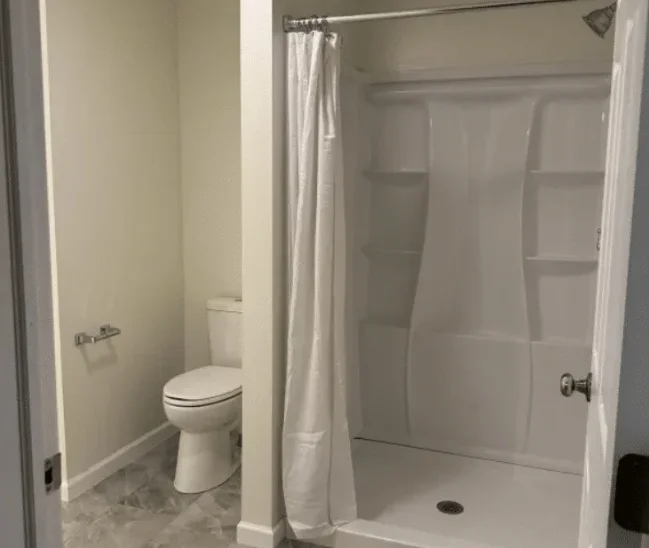 Newly remodeled bathroom with walk in shower, toilet, and modern flooring installed by professional Berks Plumbers