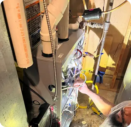 Berks Plumbing & HVAC technician repairing furnace wiring and control components inside residential home